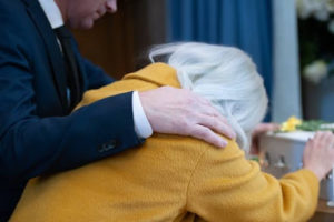 A man putting his arm around a woman grieving a lost loved one