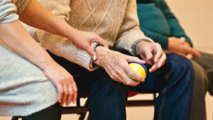 A younger woman places her hand on the arm of an elderly man