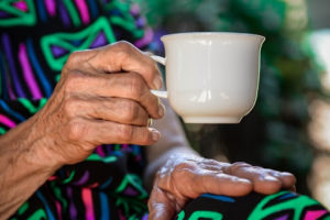 An elderly woman holds a tea cup