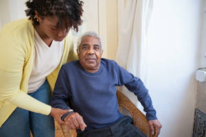 A young woman helps an old man from his seat