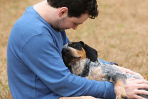 A man holds his dog and smiles