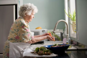A older woman prepares to cook